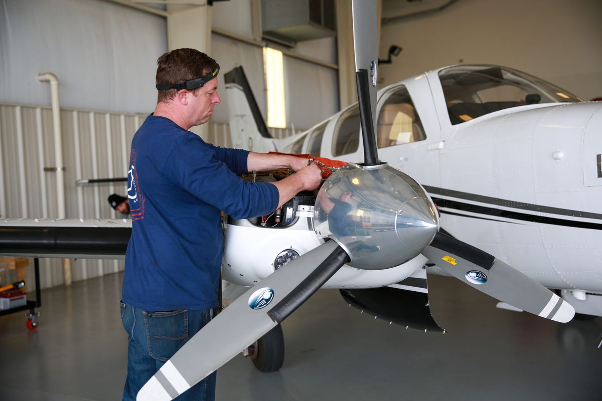 Technician inspecting a propeller on a twin-engine aircraft